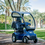 4 Wheel Mobility Scooter In Blue With Optional Solid Canopy Shown Outdoors. 4 Wheel Mobility Scooter In Blue With Optional Solid Canopy Shown Outdoors.