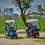 Red and Blue 3 And 4 Wheel Recreational Scooters In A Park. Red and Blue 3 And 4 Wheel Recreational Scooters In A Park.